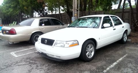 2000 Mercury Grand Marquis - Two Mercury Grand Marquis sedans parked side-by-side in a lot.