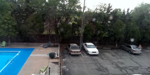 2000 Mercury Grand Marquis - Three cars are parked in a lot near a swimming pool on a cloudy day.