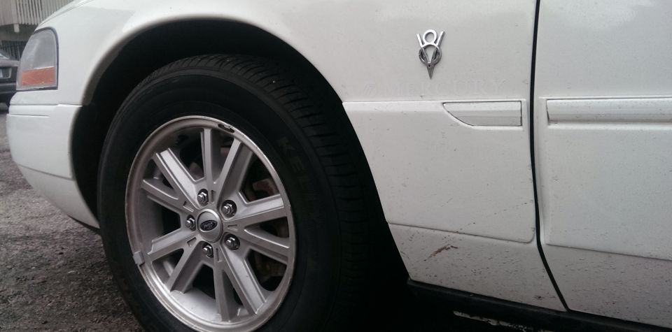 White 2000 Mercury Grand Marquis side view with V8 emblem and alloy wheel