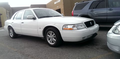 2000 Mercury Grand Marquis - A white sedan is parked in a lot next to other vehicles.