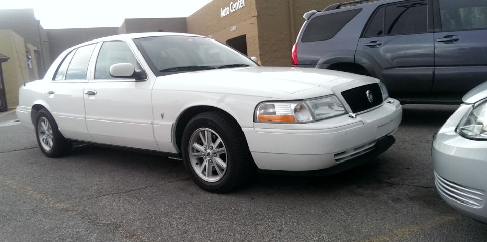 White sedan parked next to a gray SUV and a silver car