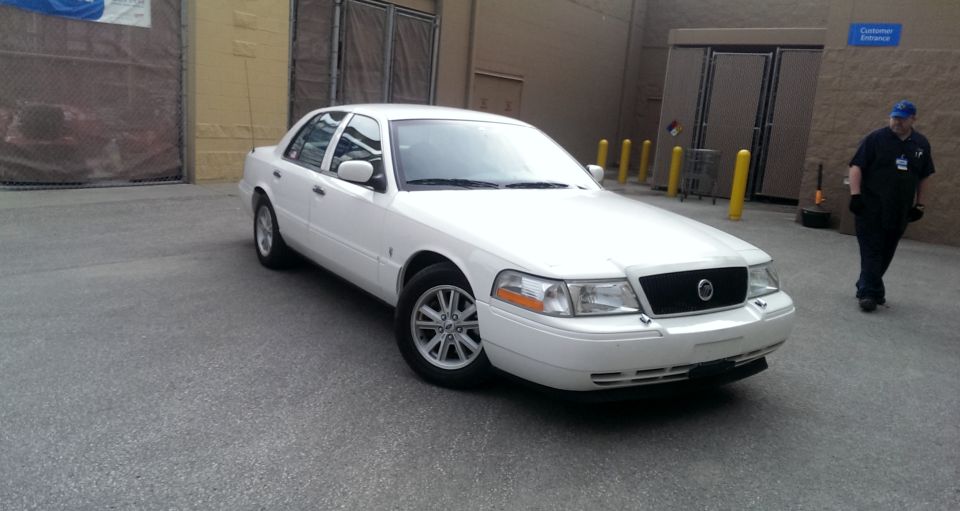 White sedan parked outside, person walking by