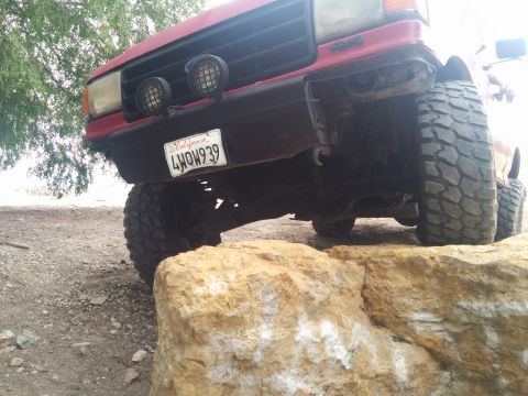 1988 Ford Bronco - 1988 Ford Bronco front view with off-road tires navigating rocks.