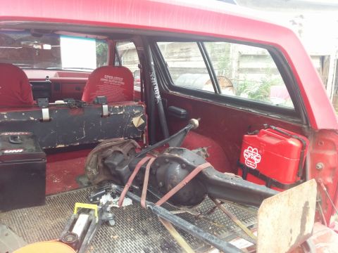 1988 Ford Bronco - The interior of a red SUV is filled with parts, including a differential, a jack, and a red gas can.