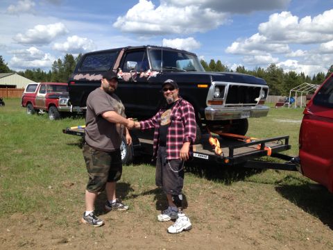 1978 Ford Bronco - Two men shake hands in front of a black Ford Bronco being transported on a trailer, with another Bronco in the background.