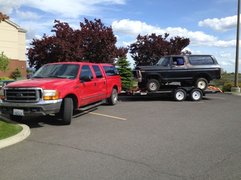 1978 Ford Bronco - A red Ford F-250 Super Duty tows a black 1978 Ford Bronco on a trailer.