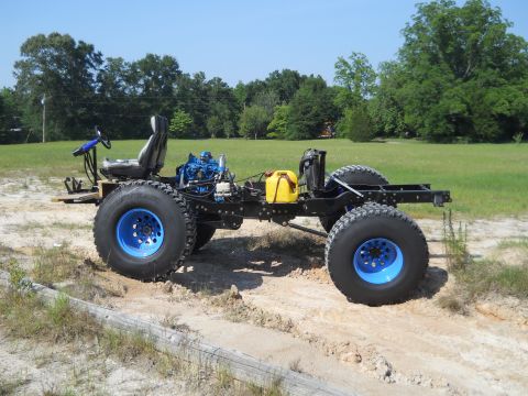 1992 Ford Bronco - This custom off-road chassis features large tires, a prominent blue engine, and a yellow fuel can, suggesting a unique build.