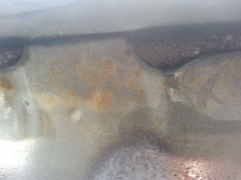 1992 Ford Bronco - Close-up of a rusted metal panel, likely from a vehicle's undercarriage or firewall.