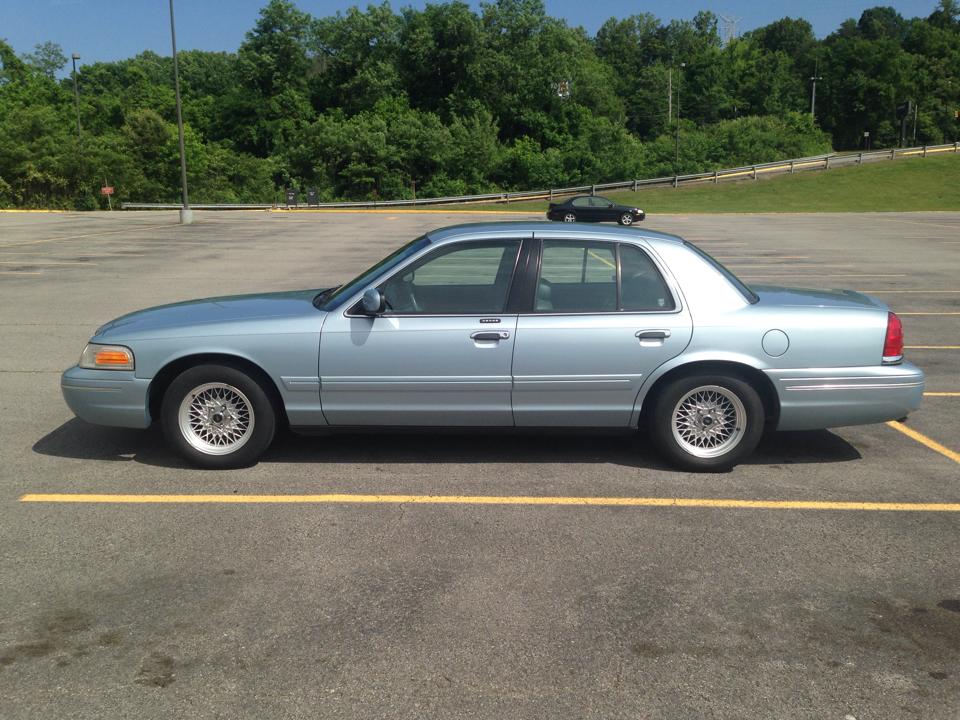 Light blue sedan parked in a lot. A small black car is on its roof