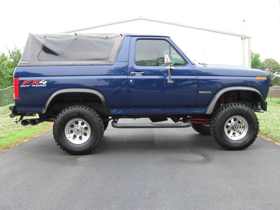 Blue Ford Bronco with FX4 Off Road decal and soft top, lifted suspension, side view