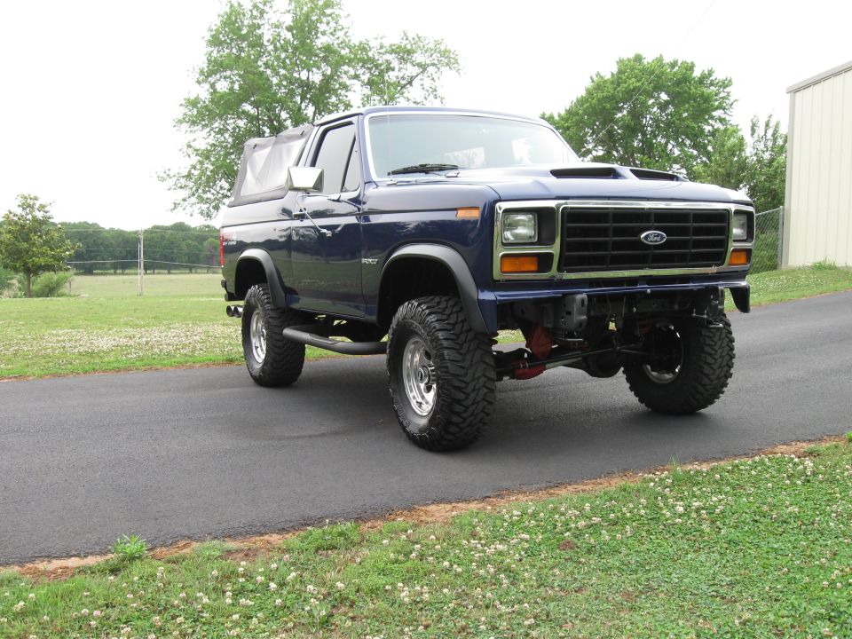 Blue lifted Ford Bronco with a soft top, 1980s body style