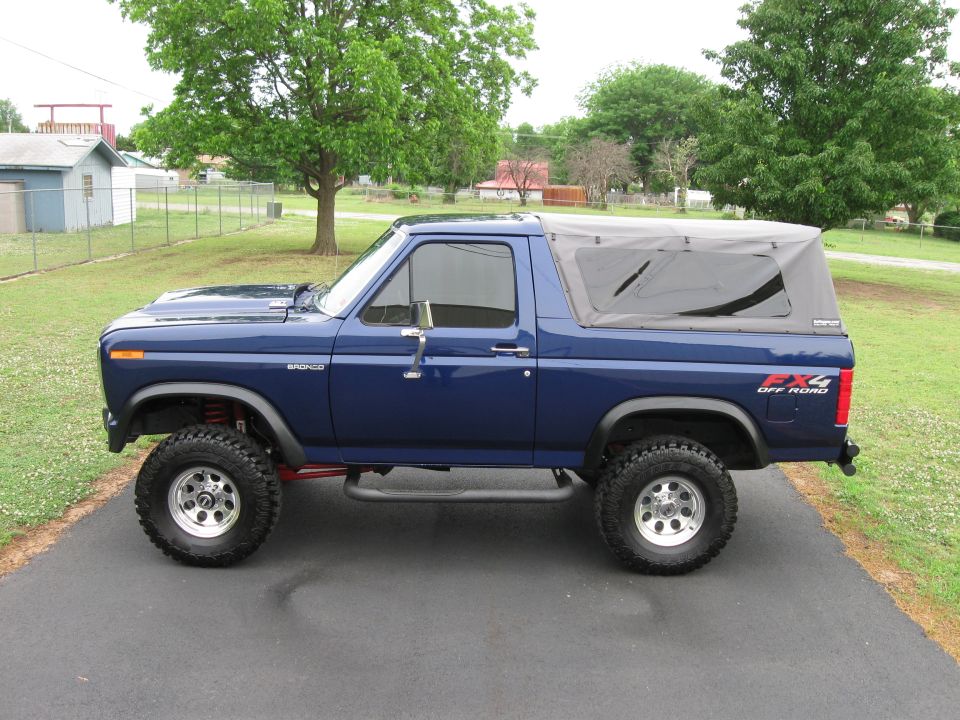 Blue Ford Bronco, lifted, with a soft top, parked on asphalt
