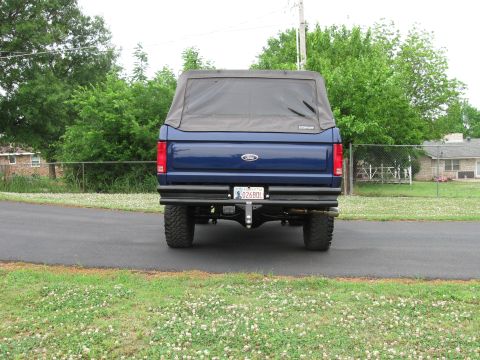 1982 Ford Bronco - Rear view of a blue Ford Bronco with a soft top and aftermarket bumper.