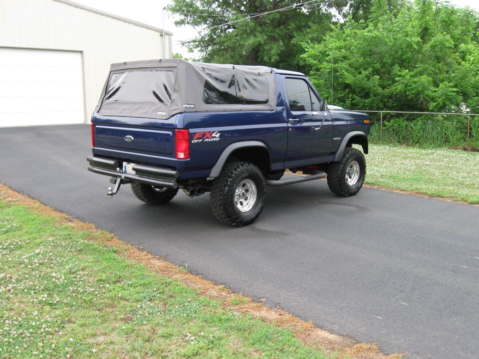 Blue Ford Bronco with soft top, lifted, parked on driveway