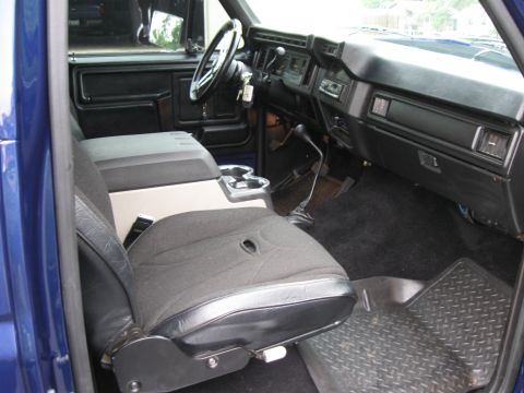 1982 Ford Bronco - The interior of a blue truck is visible, a custom center console and aftermarket seat covers.