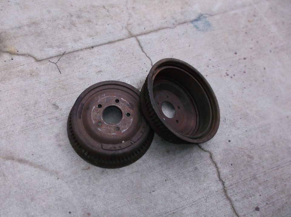 Two old, rusty brake drums sitting on a concrete surface