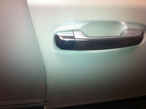 1982 Ford Bronco - Close-up of a car's side door handle, showing chrome detailing on a white exterior.