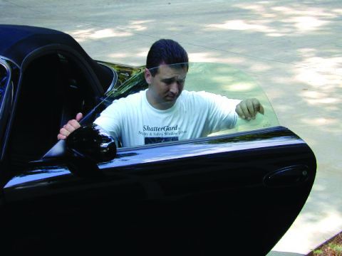 1998 Ford Crown Victoria - Man in a white t-shirt opens the driver's side door of a black car.