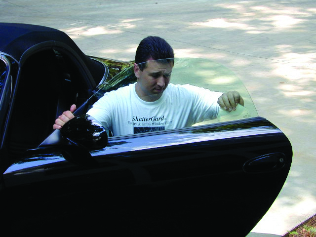 Man in white ShatterGard t-shirt opens black car door