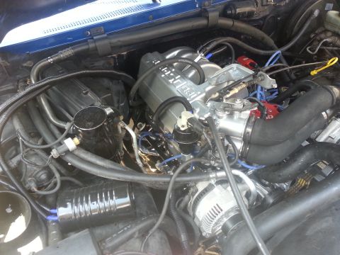1994 Ford Bronco - Close-up view of an engine bay a silver intake manifold and red spark plug wires.