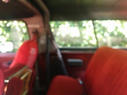 1988 Ford Bronco - The interior of a red truck shows red seats and a fire extinguisher mounted on the pillar.