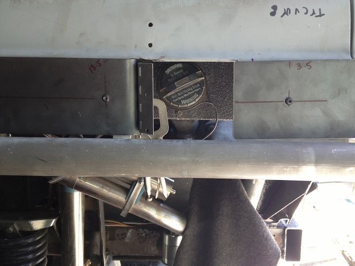 Fuel filler cap with warning text, mounted on metal chassis with measurement markings