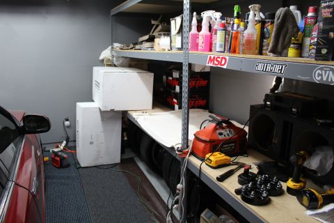 2003 Ford Crown Victoria - Garage shelving stocked with MSD and Race Star boxes, drills and tools, with a red car parked alongside.