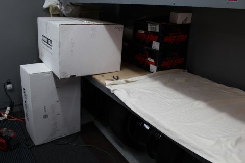 2003 Ford Crown Victoria - White cardboard boxes on a cloth-draped garage shelf beside stacked Race Star product boxes.