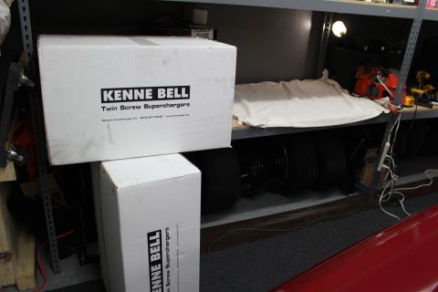 2003 Ford Crown Victoria - White Kenne Bell Twin Screw Supercharger boxes on a garage shelf above stacked black tires and tools.