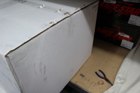 2003 Ford Crown Victoria - large white cardboard box on a cloth-draped shelf next to Race Star boxes, with blue pliers resting nearby.