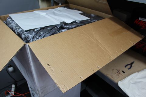 2003 Ford Crown Victoria - opened cardboard box flap folded back to show white paper and crumpled black plastic packing material.