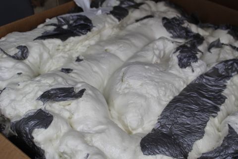 2003 Ford Crown Victoria - Close-up of mounded white packing foam with strips of crumpled dark plastic running through it.