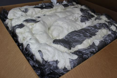 2003 Ford Crown Victoria - cardboard box packed full of mounded white foam framed by crumpled dark plastic at the edges.
