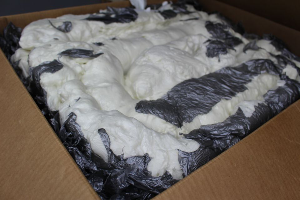 Cardboard box filled with white packing foam and dark plastic edging