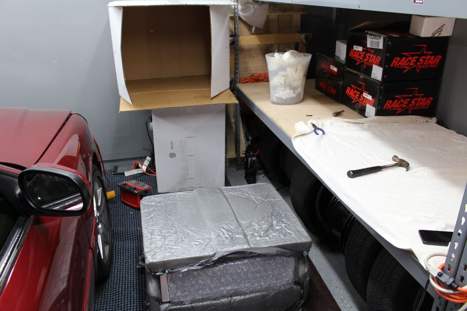 Garage scene with red car, foil-wrapped package, tires, and Race Star wheel boxes