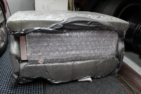 2003 Ford Crown Victoria - heavy package sheathed in silver foil and bubble wrap, bound with gray tape, on a garage floor.