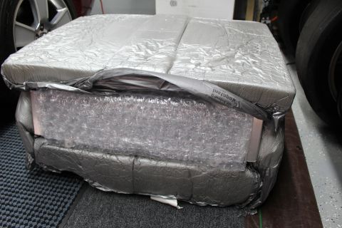 2003 Ford Crown Victoria - padded package wrapped in silver foil and bubble wrap, secured with gray tape, on ribbed shop matting.