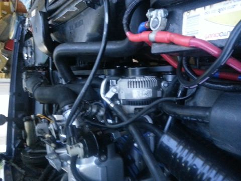 1994 Ford Bronco - Close-up view of an engine bay, showing the alternator, battery, and various hoses and wiring.