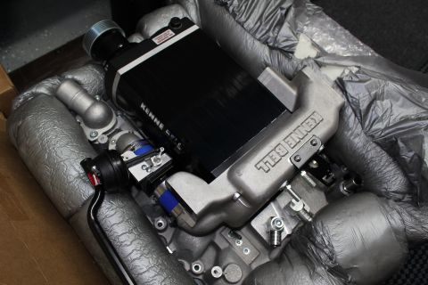 2003 Ford Crown Victoria - Angled view of a Kenne Bell supercharger assembly with its black intercooler core and Kenne Bell-branded aluminum manifold.