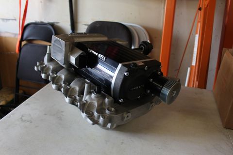2003 Ford Crown Victoria - Side profile of a Kenne Bell supercharger and aluminum intake manifold resting on a workbench in a garage.