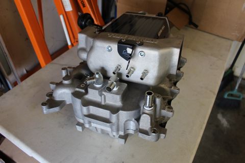 2003 Ford Crown Victoria - underside of a Kenne Bell cast aluminum intake manifold reveals its runner ports and coolant fittings on a workbench.