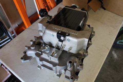 2003 Ford Crown Victoria - Kenne Bell supercharger manifold with coolant fittings, studs and a bypass valve sits on a workbench in a garage.