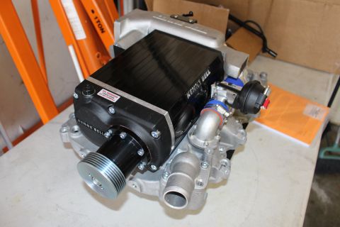 2003 Ford Crown Victoria - complete black Kenne Bell supercharger with a large ribbed snout pulley assembled on a cast-aluminum intake manifold on a bench.