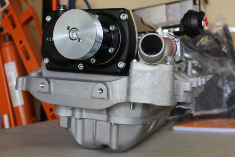 2003 Ford Crown Victoria - front three-quarter view of a supercharger with a polished pulley and black gear case mounted on a finned cast-aluminum manifold.
