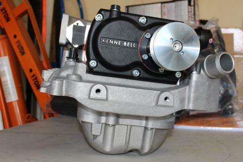 2003 Ford Crown Victoria - black Kenne Bell gear case with a polished pulley sits on a ribbed cast-aluminum manifold, photographed at an angle in a workshop.