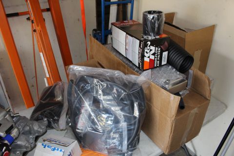 2003 Ford Crown Victoria - K&N high-flow air filter box, polished air horn, and bagged components rest atop cardboard boxes in a garage.