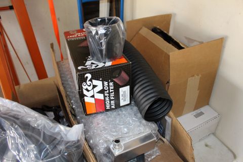 2003 Ford Crown Victoria - K&N high-flow air filter box sits beside a chrome air horn and coiled black flex tubing on cardboard boxes.