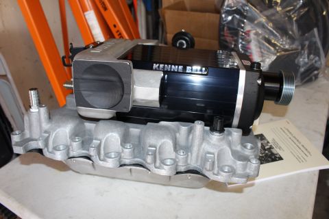 2003 Ford Crown Victoria - Top view of a Kenne Bell supercharger showing its throttle body opening and drive pulley on a cast aluminum intake manifold.