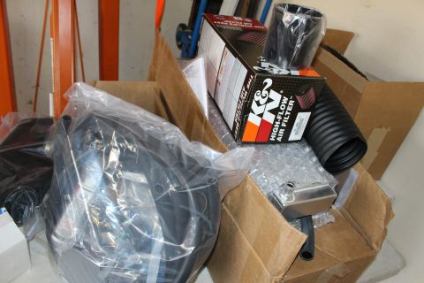 2003 Ford Crown Victoria - K&N high-flow air filter box and bagged supercharger kit parts sit in open cardboard boxes in a garage.