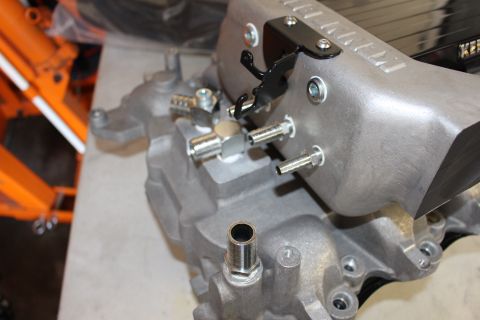 2003 Ford Crown Victoria - Close-up of a cast aluminum intake manifold showing mounting studs, a steel fitting, and a black bracket near the supercharger.